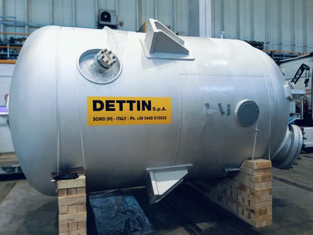 En aluminiumtryckkärl på en pall med Dettin S.p.A. märkning, avsedd för industriella processer. Kärlet har olika anslutningar och är konstruerat för att hantera höga tryck, vilket visar på avancerad materialteknik.